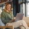 a woman sitting with a laptop near windows